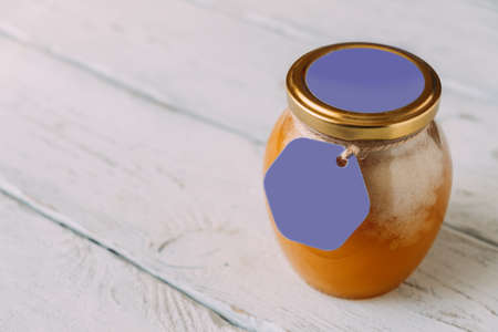 Glass jar with candied natural honey on table. Purple labels with color of the year for inscription text. copy spaceの写真素材