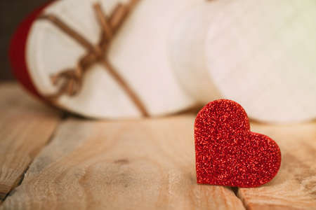 Small red decorative heart on wooden table against background of gift boxes. Gift to loved one.の写真素材