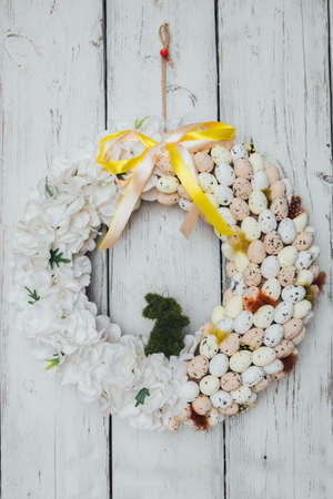 Light wreath as decoration for Easter. White Easter wreath with eggs, flowers and a green rabbit.の写真素材