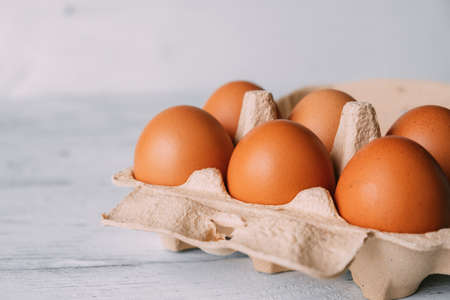 Cardboard egg storage box with brown chicken eggs close-up.