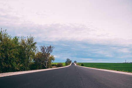 New asphalt road along fields and trees.の写真素材