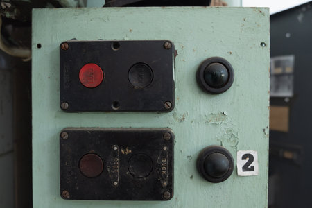 The old control panel with a close -up of two buttons and a metal plate. The red button with the...