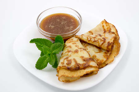 Crepes on a white plate with mint leaves and a Cup of honeyの写真素材