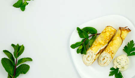 Crepes with cheese sauce on a white plate with mint leavesの写真素材