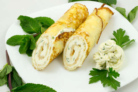 Crepes with cheese sauce on a white plate with mint leavesの写真素材