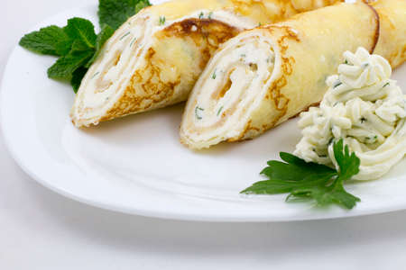 Crepes with cheese sauce on a white plate with mint leavesの写真素材