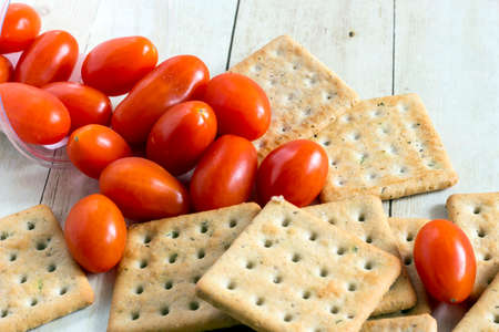 Cherry tomatoes with crackers on light wood backgroundの写真素材