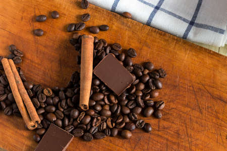 Coffee in white plastic glass with background of coffee beans, chocolate chunks and cinnamon sticksの写真素材
