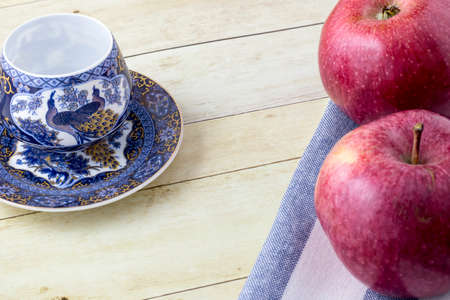 Cup of tea with red apples on cloth napkin in light wood backgroundの写真素材
