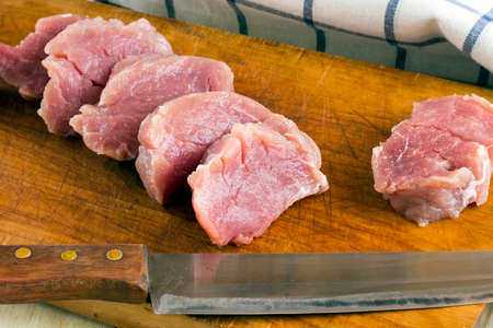 Cut fresh pork on wood board with background of salt and black pepperの写真素材