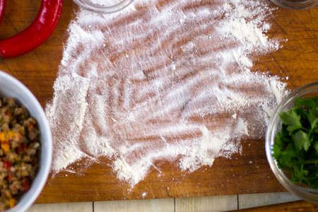 Empanadas cooking preparations: flour with spices, culinary herbs and minced pork on wood boardの写真素材
