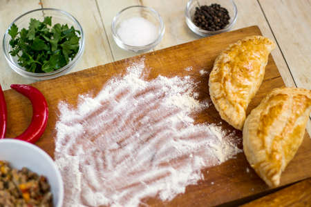 Empanadas cooking preparations: flour with spices, culinary herbs and minced pork on wood boardの写真素材