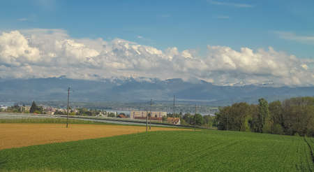 Amazing landscape with green field, mountains and cloudsの写真素材