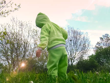 A child in a green suit walks on a green lawnの写真素材