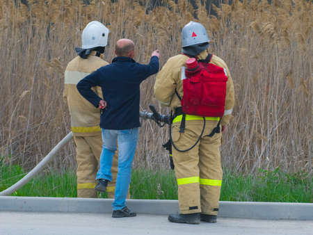 Two firefighters and a man showing somewhereの写真素材