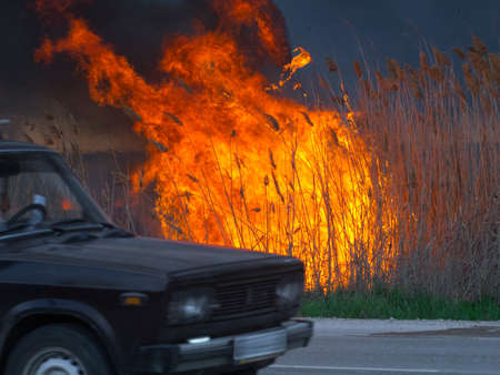 The car is driving along the road near the fireの写真素材