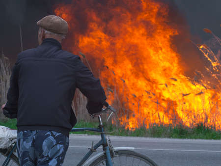 A cyclist looks at a fire near a roadの写真素材