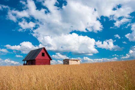 Standing house of bars stands in a field against the background of autumn grass and blue sky with clouds.の写真素材