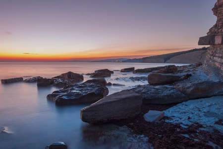 Seascape at sunset. Sea on a long shutter with stones and rocks.の写真素材