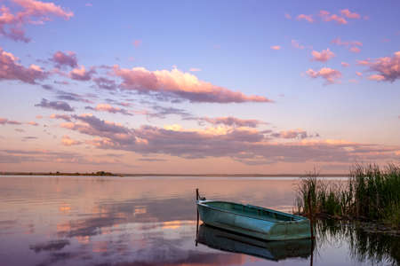 Beautiful landscape with boats on the lake and clouds in the sunset sky.の写真素材