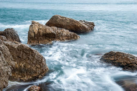 Seascape of the Crimean coast. Waves break into beautiful splashes against rocks.の写真素材