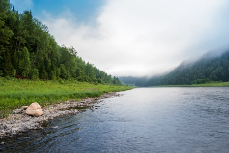 Landscapes of Siberia. Early morning on the Kiya river. Fog descends on the river over the taiga....