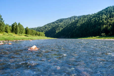 Landscape of Siberia. Kiya River, mountain banks and green forests in the Kemerovo region. Daytime landscape with blue skies and clouds.の写真素材