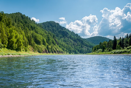 Landscape of Siberia. Kiya River, mountain banks and green forests in the Kemerovo region. Daytime landscape with blue skies and clouds.の写真素材