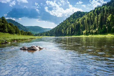 Landscape of Siberia. Kiya River, mountain banks and green forests in the Kemerovo region. Daytime landscape with blue skies and clouds.の写真素材