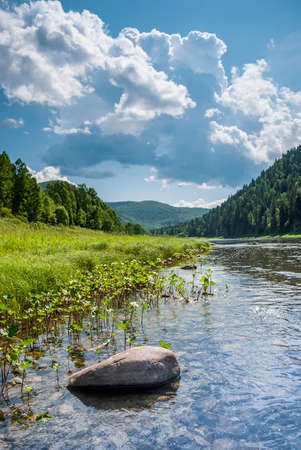 Landscape of Siberia. Kiya River, mountain banks and green forests in the Kemerovo region. Daytime landscape with blue skies and clouds.の写真素材
