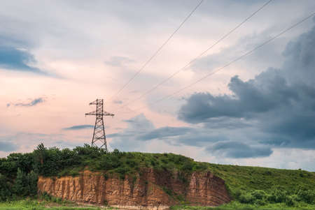 Landscapes of Siberia. The tower of the high-voltage line on a hill against the background of sunset sky.の写真素材