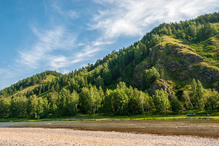 Landscape of Siberia. Kiya River, mountain banks and green forests in the Kemerovo region. Daytime landscape with blue skies and clouds.の写真素材