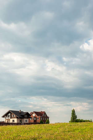 Summer landscape. Several cottages in the field against the background of a thunderstorm sky.の写真素材