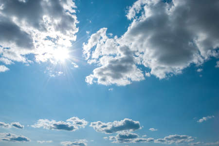 Beautiful, blue summer sky with fluffy clouds and bright sun as a backgroundの写真素材