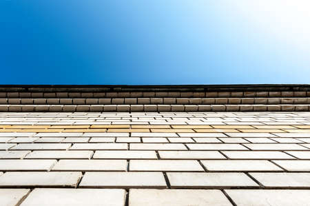 A white brick wall, shot from the bottom up, against a clear blue sky. Place for signature.の写真素材