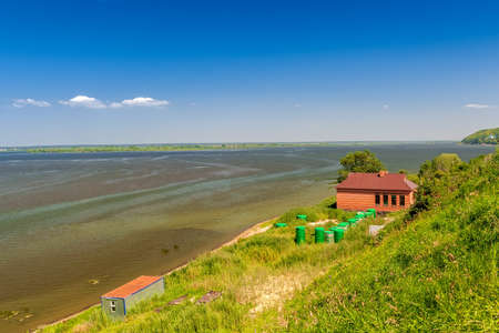 A brick building and green metal barrels with a combustible mixture on the shore of the lake.の写真素材