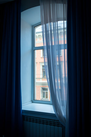 A window with blue curtains and a beautifully falling tulle.の写真素材