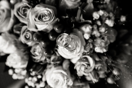 A pair of wedding rings on a bouquet of colorful flowers, close up shotの写真素材