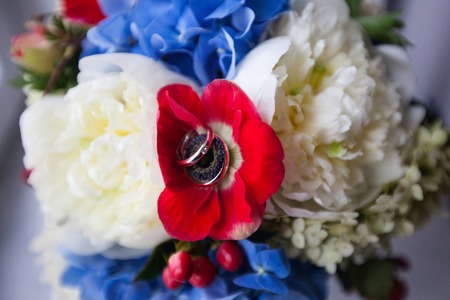 A pair of wedding rings on a bouquet of colorful flowers, close up shotの写真素材