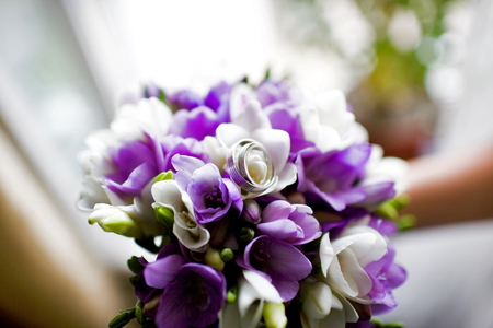 A pair of wedding rings on a bouquet of colorful flowers, close up shotの写真素材