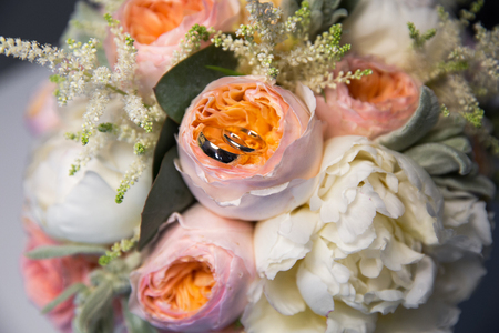 A pair of wedding rings on a bouquet of colorful flowers, close up shotの写真素材