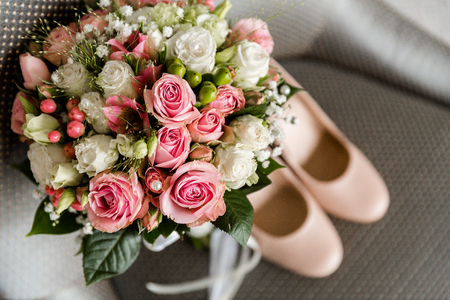 Wedding bouquet of white and pink roses on a blurred background of the brides shoesの写真素材