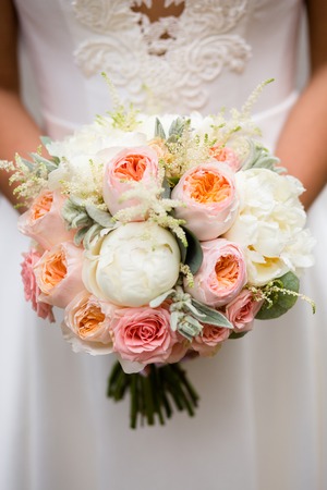 Wedding bouquet of white and cream peonies in the hands of the brideの写真素材