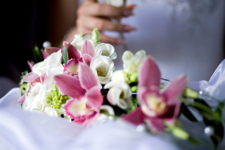 Bouquet of pink orchids and white freesia on the background of the brideの写真素材