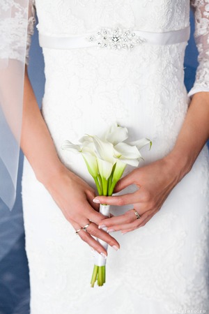 Exquisite bridal bouquet of white callas in the hands of an unrecognizable brideの写真素材