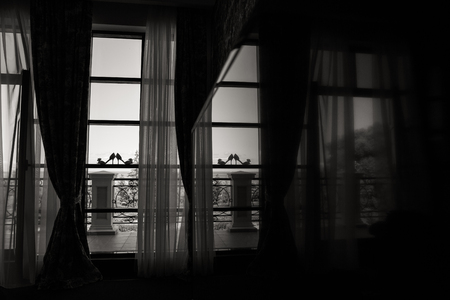 Silhouette of female shoes on a window with a terrace and with reflection in a mirror, black and white shotの写真素材