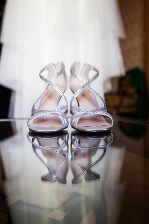 White women's shoes with rhinestones on high heels with a reflection on the mirror surface, on a blurred background of a wedding dressの写真素材