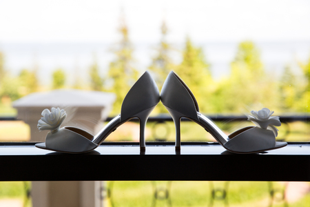 Women's white shoes on the window, on a blurred background of green treesの写真素材