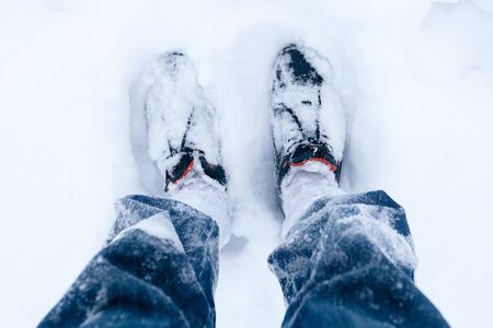 Mans legs in blue jeans and black shoes outdoors in the snowの写真素材