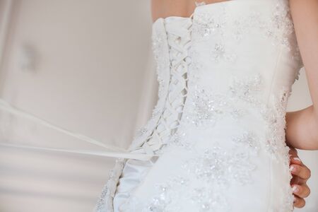 Bride from the back. Lacing the wedding dress.の写真素材